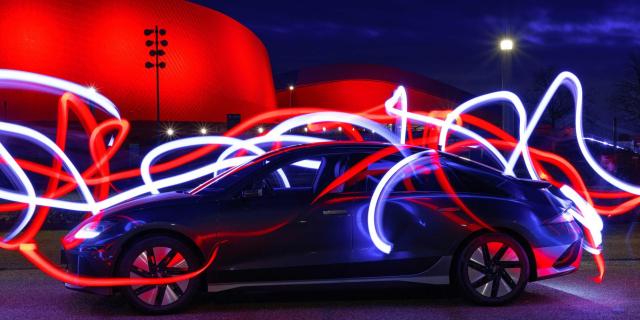 an electric vehicle surrounded by lines of color in the night