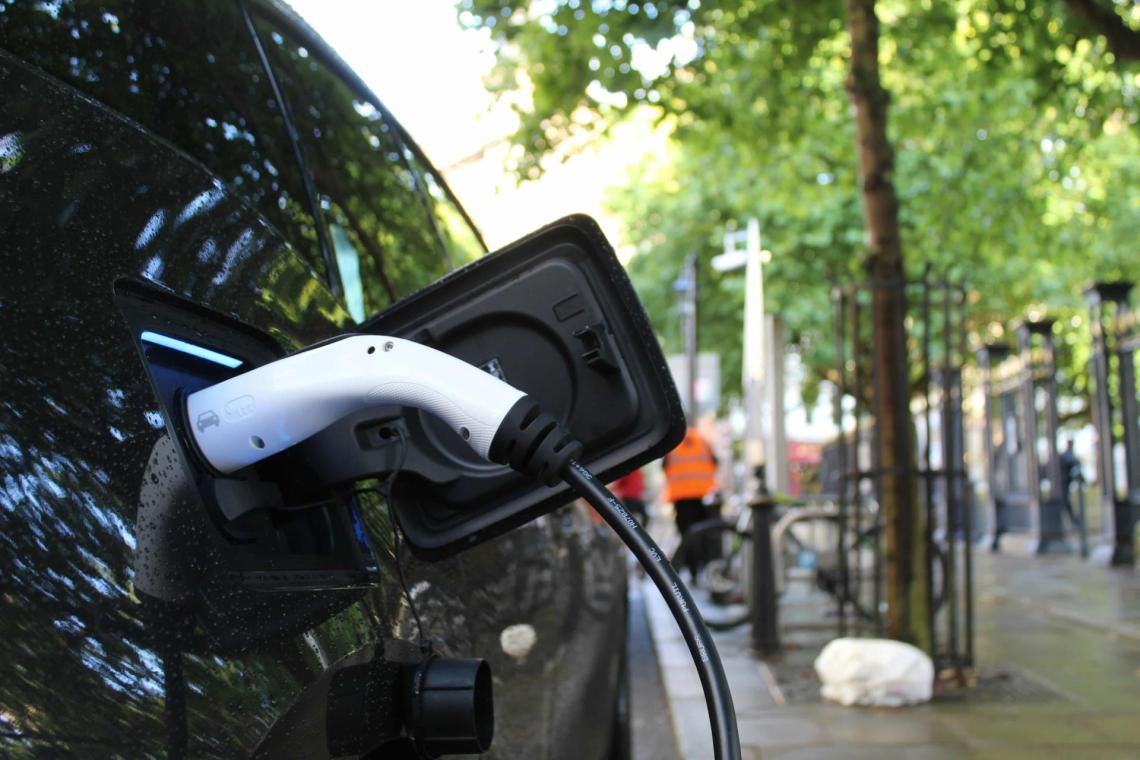 A close up photo of the charging port of an electric car. The charging cable is plugged in